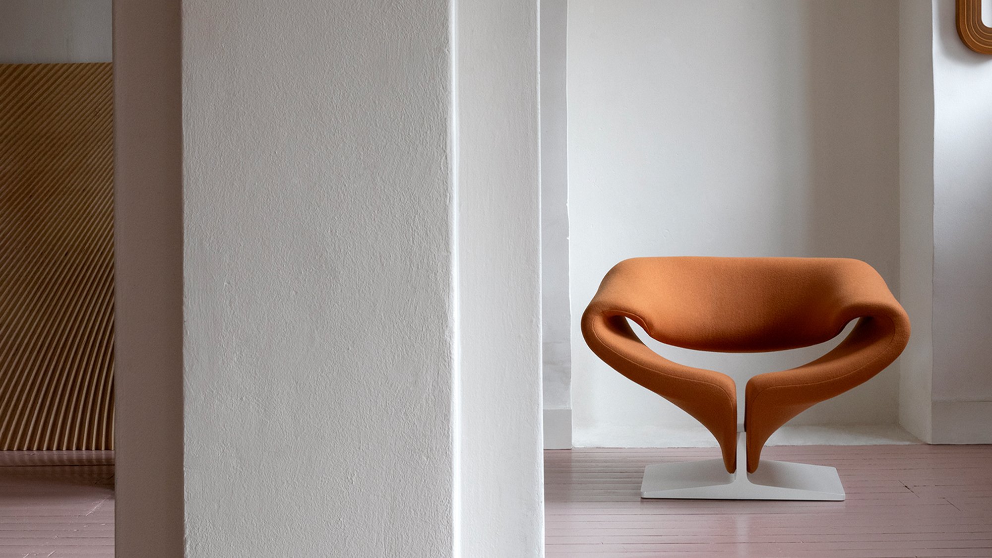 Warm orange Ribbon chair by Pierre Paulin at the end of a quiet architectural room